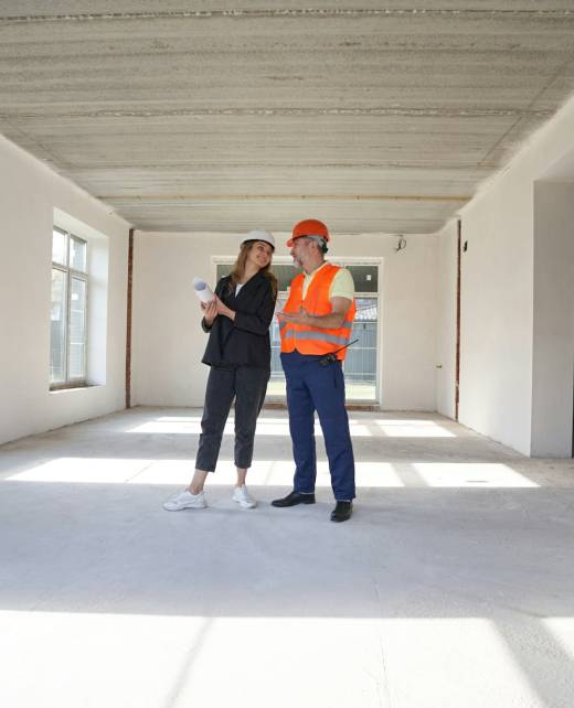 Woman engineer talking with construction worker inside house